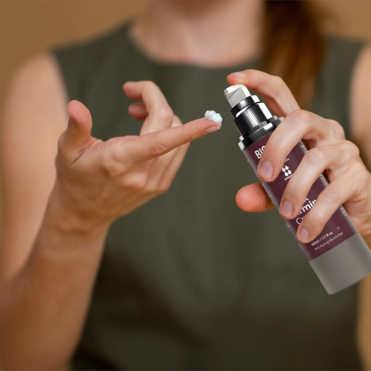 Person applying a white cream to their hand using a spray bottle.