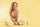 Woman sitting on a yellow background with a bottle of vitamin c